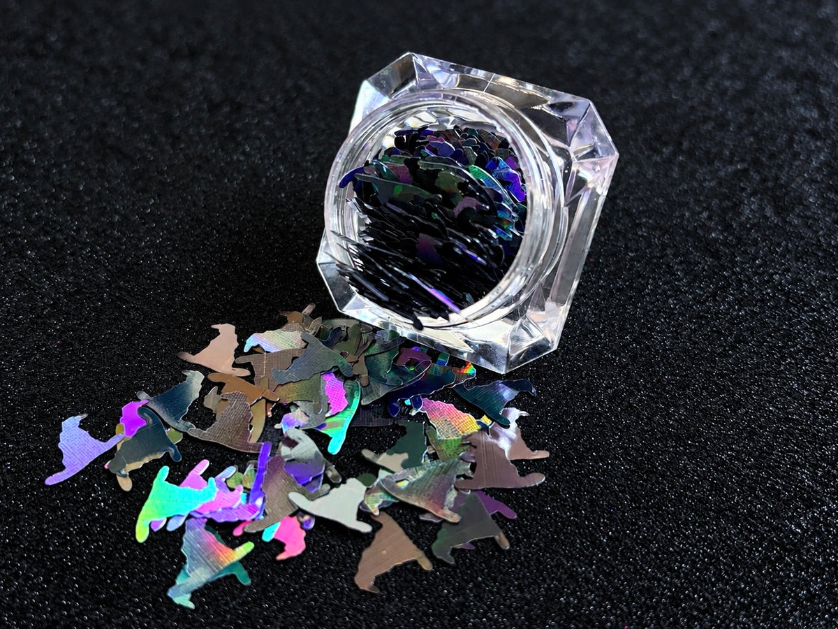 10mm holographic black witch hat glitter shapes spilled from a clear jar onto a black textured background.