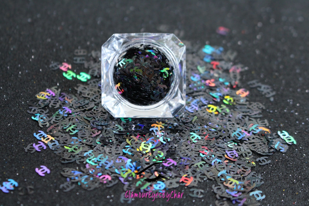 This glitter is called CC and is part of the shaped glitters collection. It consists of unique Chanel designer inspired holographic black CC letters. CC can be used for body and nail art or DIY projects. Available in 5g jars only.