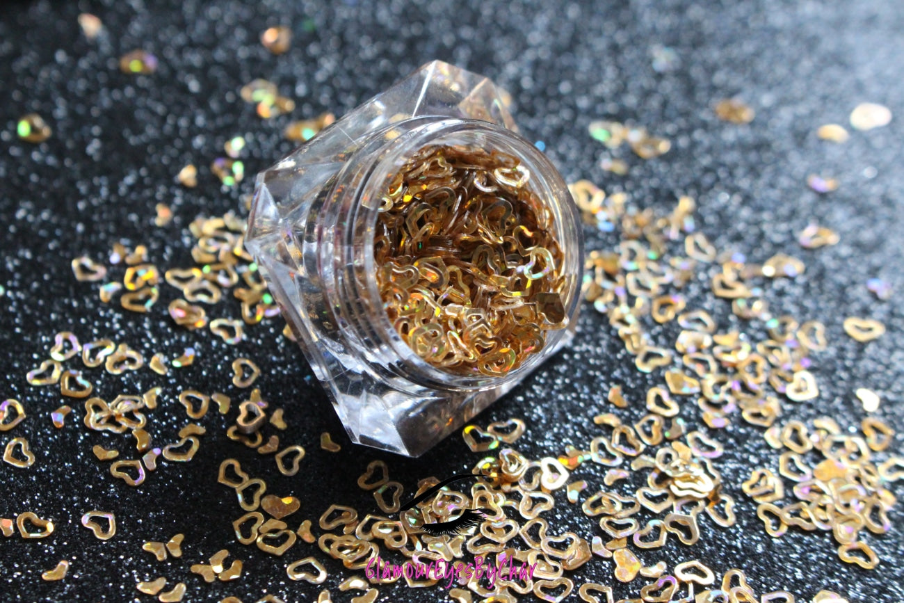 This glitter is called Holographic Gold Hearts and is part of the shaped glitters collection. It consists of gold small and large hearts with a holographic sparkle. Holographic Gold Hearts is perfect for nail and body art.