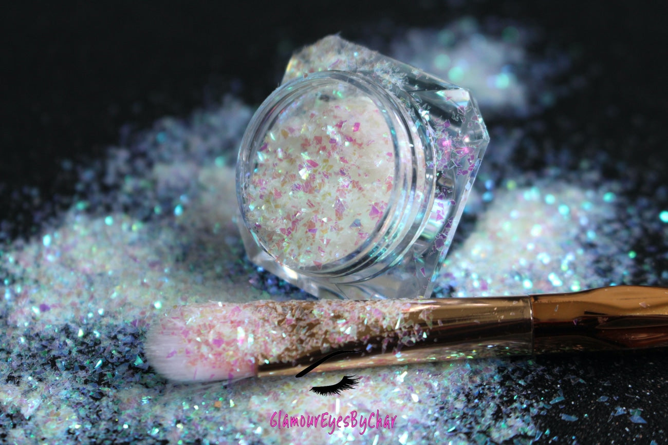 This glitter is called Soft Touch and is part of the cellophane glitter flakes collection. It consists of white iridescent glitter shards with purple and green reflects. Soft Touch is perfect for body and nail art, glitter slime, resin art or DIY projects. Comes in 5g jars only.