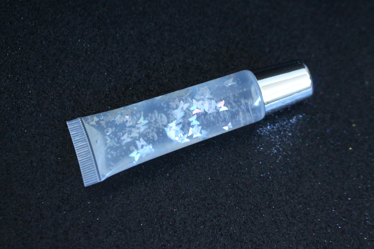 Crystal Clear is a clear handmade hydrating gloss with silver holographic butterflies. This gloss is also vegan, cruelty-free, gluten-free, high shine, smooth and long lasting. It's made with premium rich ingredients to keep your lips soft, moisturized and luscious without feeling sticky. Crystal Clear is available in a squeeze tube and a wand tube (flat doe foot applicator) for a more precise application.