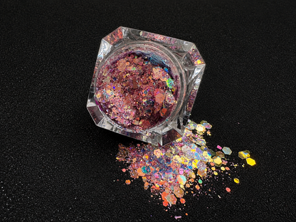 Top-down view of super chunky pastel purple glitter mix with rose gold iridescent color shift, spilled from a clear jar onto a black textured background.