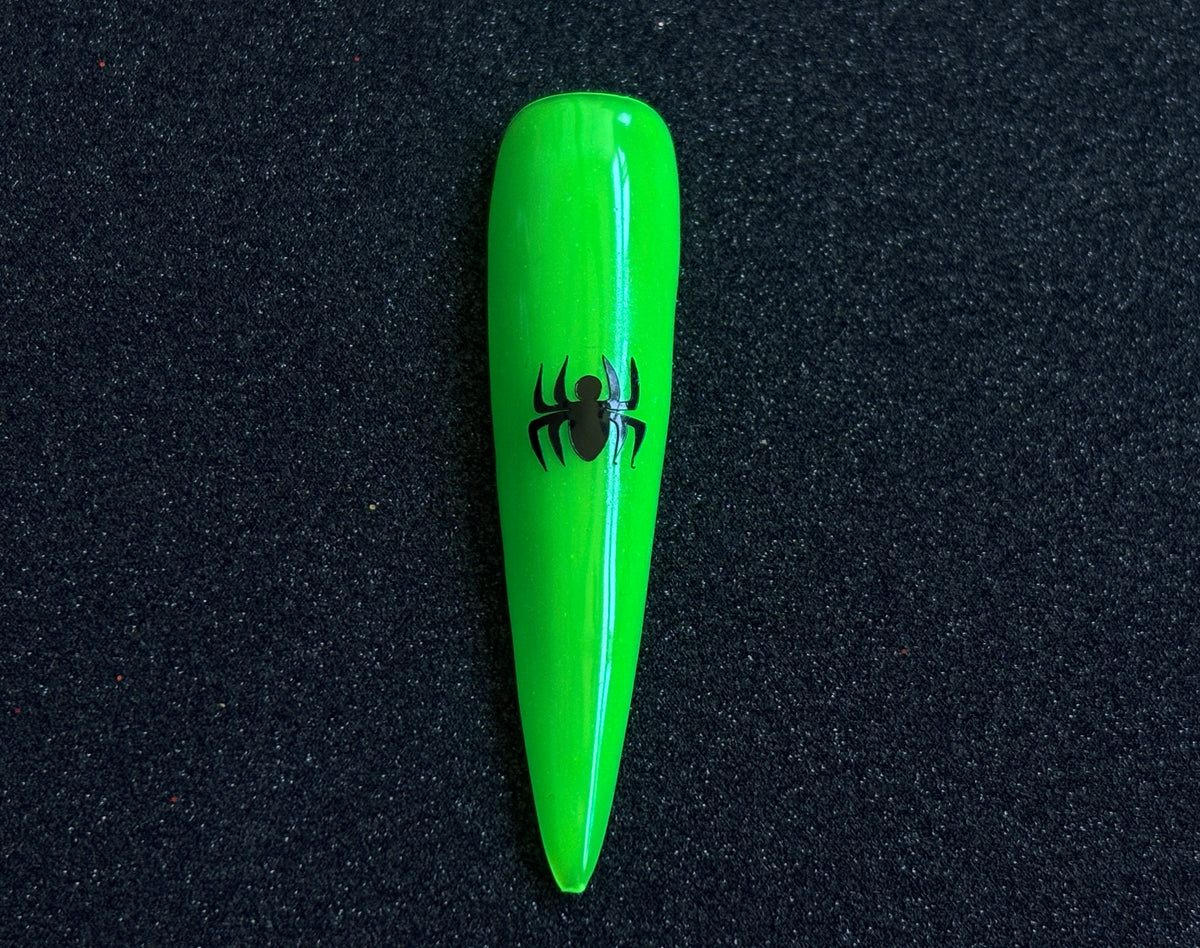 Black spider nail sticker applied on a bright green stiletto nail tip against a black textured background.