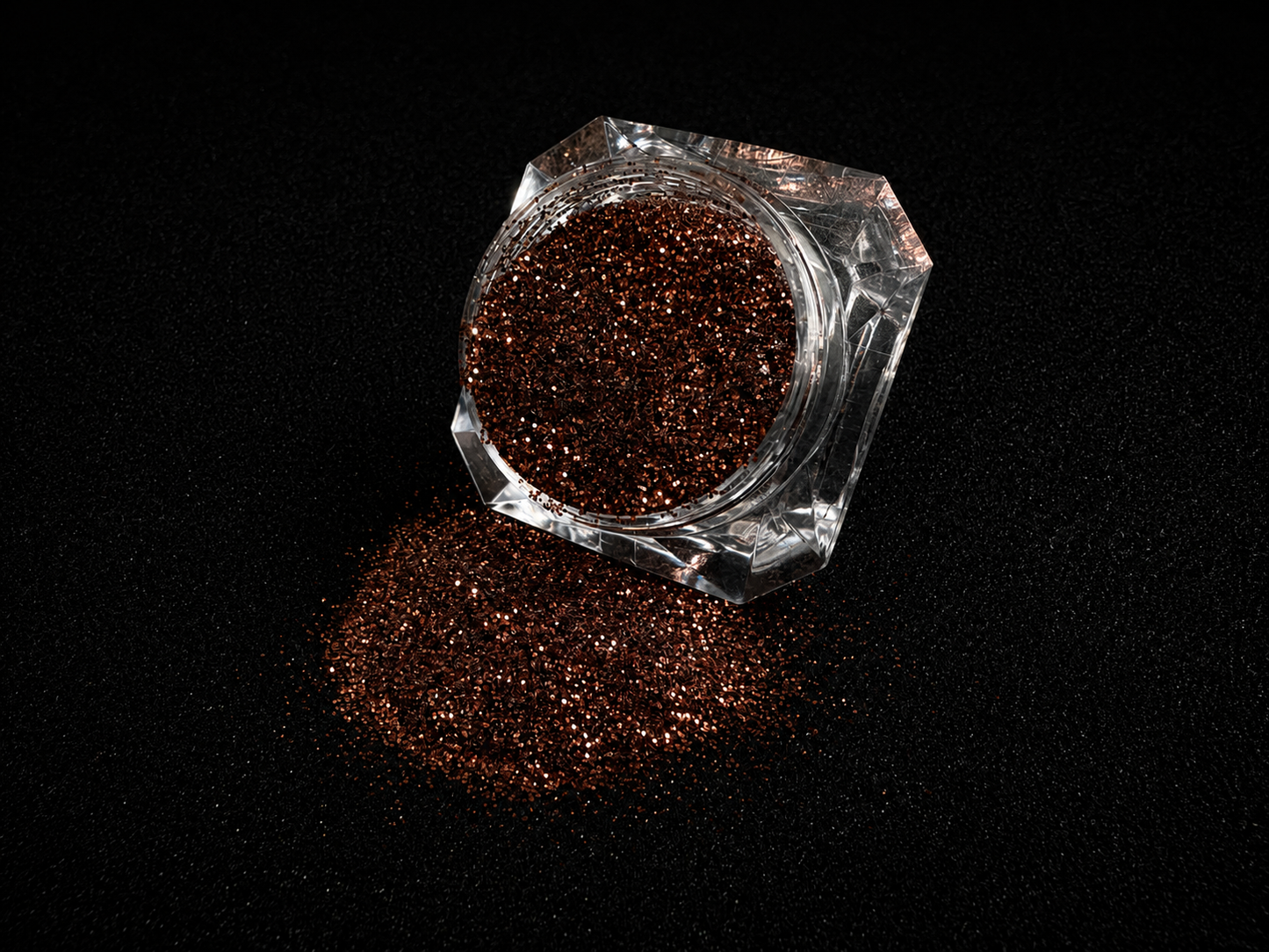 Chocolate brown metallic glitter spilled from a clear jar onto a black textured background.