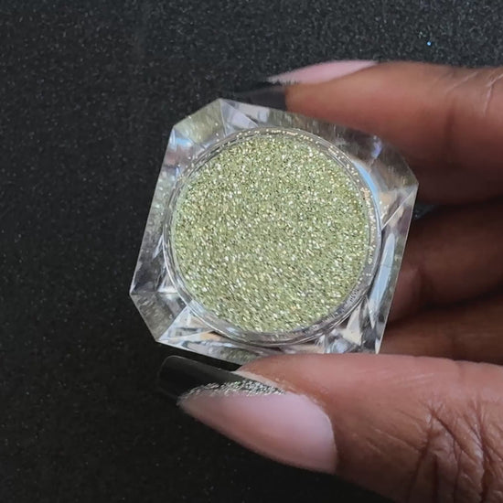 Champagne gold and silver glitter mix in a clear jar, tilted back and forth to show sparkle against a black background.