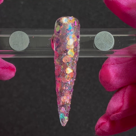 Super chunky pastel purple glitter mix with rose gold iridescent colour shift applied on a stiletto nail tip, tilted to show sparkle.