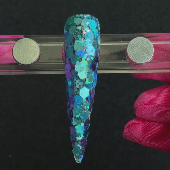 Super chunky holographic dark aqua glitter mix applied on a stiletto nail tip, tilted to show sparkle.