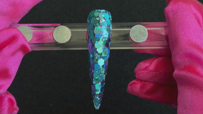 Super chunky holographic dark aqua glitter mix applied on a stiletto nail tip, tilted to show sparkle.