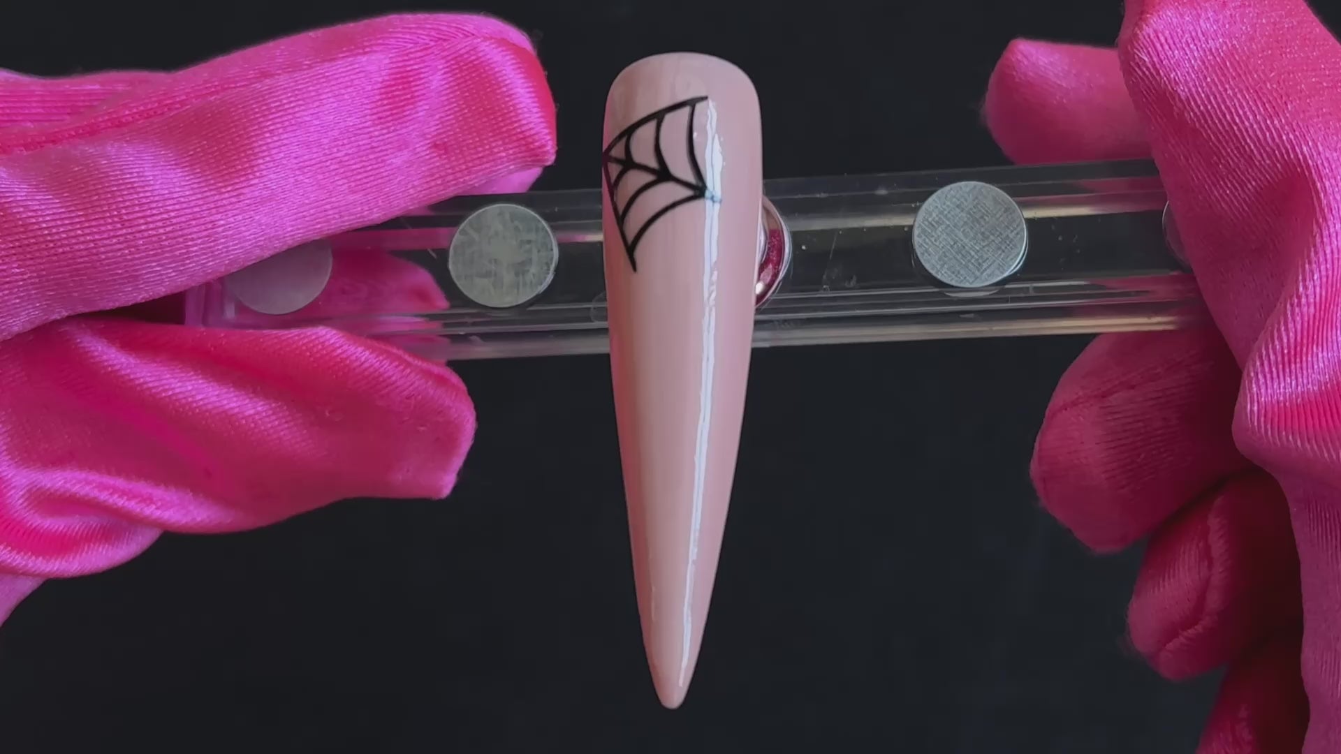 Black cobweb Halloween nail sticker on a glossy nude stiletto nail tip, tilted back and forth to show the finished nail design.