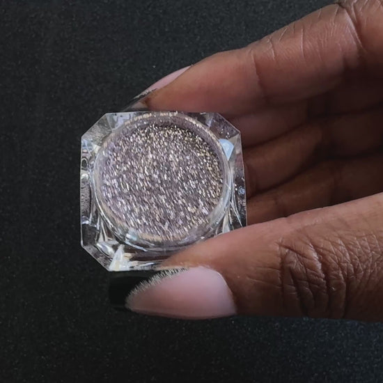 Champagne pink glitter in a clear jar, tilted back and forth to show sparkle against a black background.