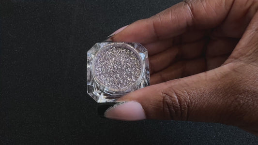 Champagne pink glitter in a clear jar, tilted back and forth to show sparkle against a black background.
