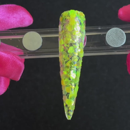 Fluorescent iridescent green super chunky glitter mix with yellow shift applied on a stiletto nail tip, tilted back and forth to show sparkle.