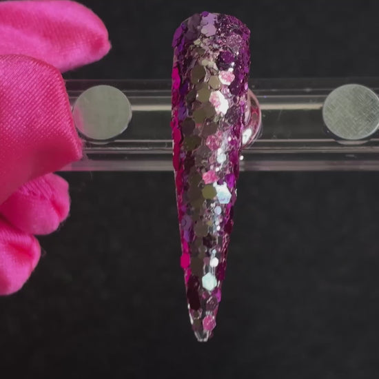 Purple super chunky glitter mix with pale gold colour-shifting sparkle applied on a stiletto nail tip, tilted back and forth to show sparkle.