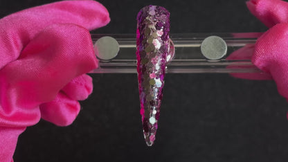 Purple super chunky glitter mix with pale gold colour-shifting sparkle applied on a stiletto nail tip, tilted back and forth to show sparkle.