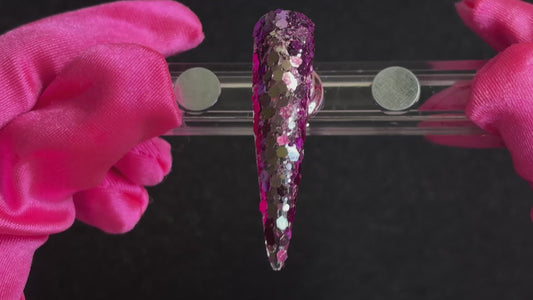 Purple super chunky glitter mix with pale gold colour-shifting sparkle applied on a stiletto nail tip, tilted back and forth to show sparkle.