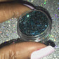 This glitter is called Pure Poison and is part of the chunky glitter collection. It consists of black holographic glitter with a teal and aqua sparkle. Pure Poison can be used for your face, body, hair and nails.  Comes in 5g and 10g jars. **Glitter will be discontinued once sold out**