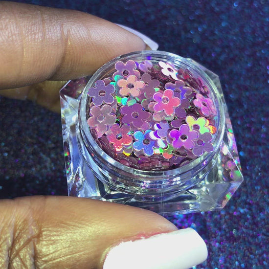 This glitter is called Lilac Holographic Flowers and is part of the shaped glitters collection. It consists of lilac flowers with a holographic sparkle. Lilac Holographic Flowers is perfect for nail and body art.
