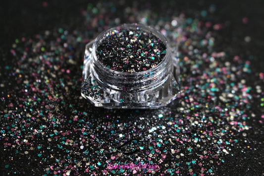This glitter is called Drama Queen and is part of the chunky glitter collection. It consists of black holographic glitter with a multi-coloured sparkle. Drama Queen can be used for your face, body, hair and nails.  Comes in 5g and 10g jars.